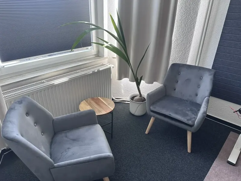RaumEINS (10 m²) mit Sesseln und Pflanze am Fenster